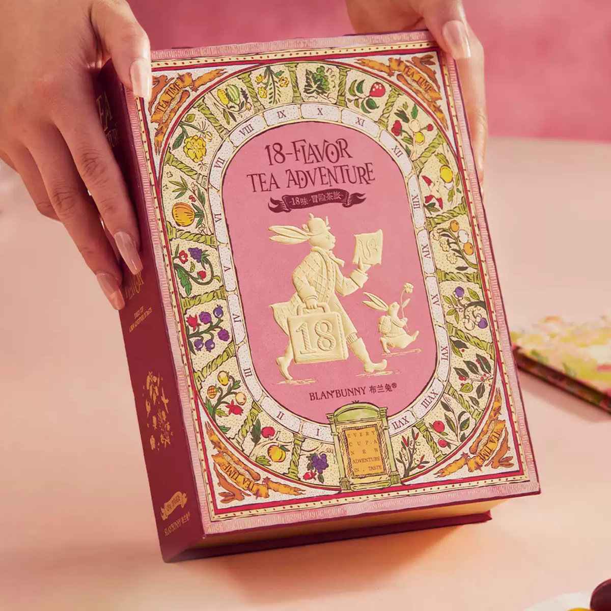 18-Flavour Adventure Tea Journey illustrated closed book-style gift box held in two hands
