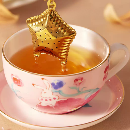 Flower Goddess's Basket gold star tea infuser above a cup of tea