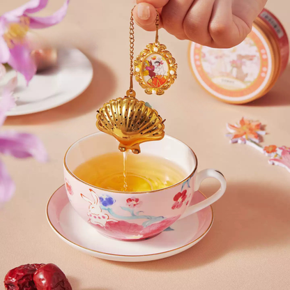 Nightingale and Rose shell-shaped tea infuser over a cup of tea